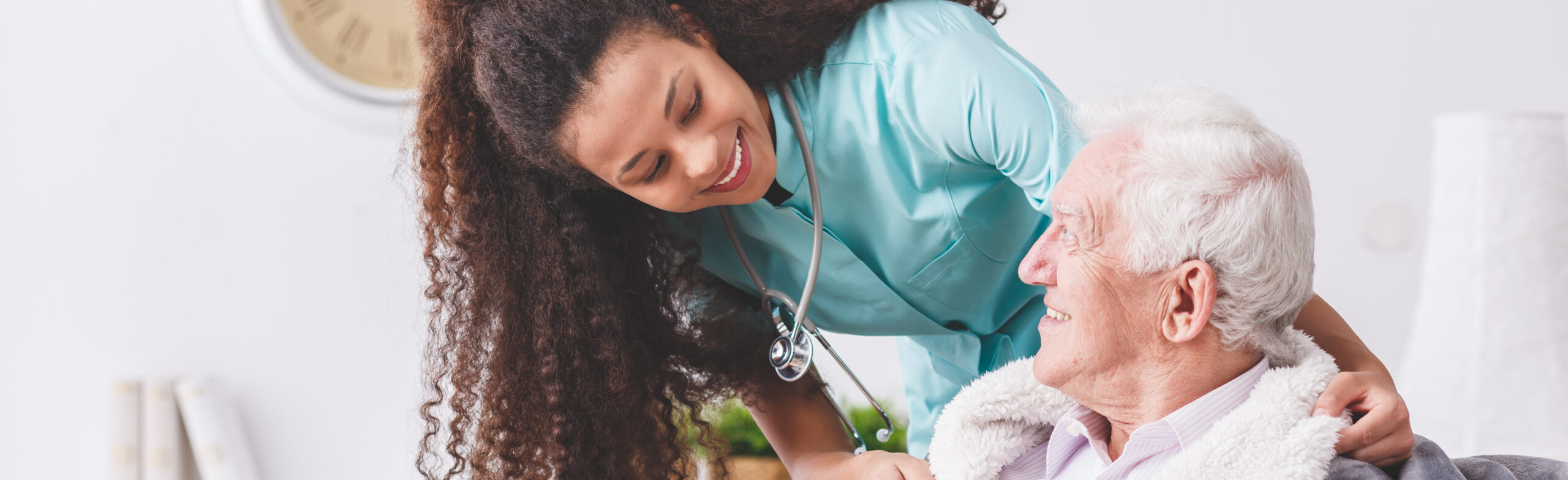 Panorama of a happy nurse with a stethoscope covering an elderly